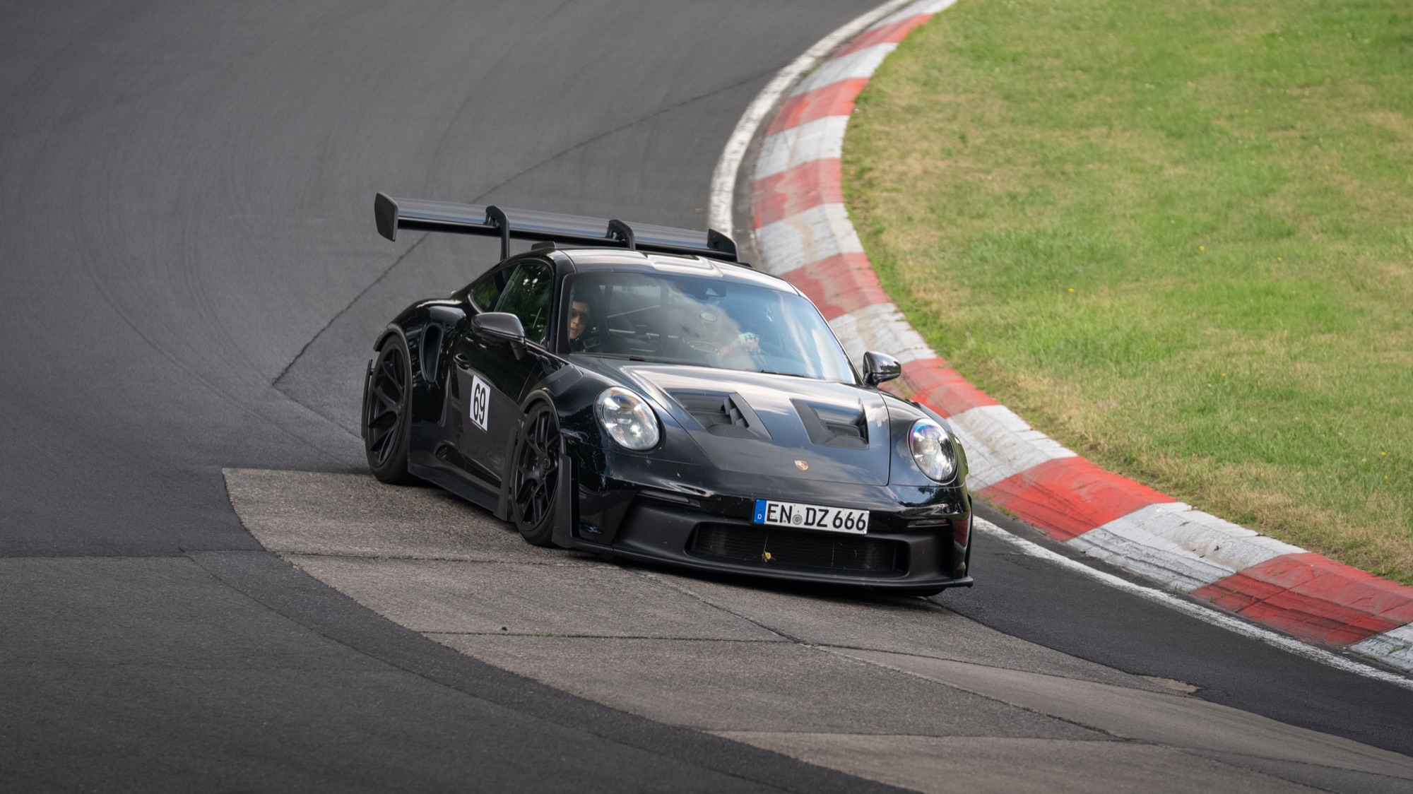Black Porsche 911 GT3 RS on the Nürburgring, kerb and wing