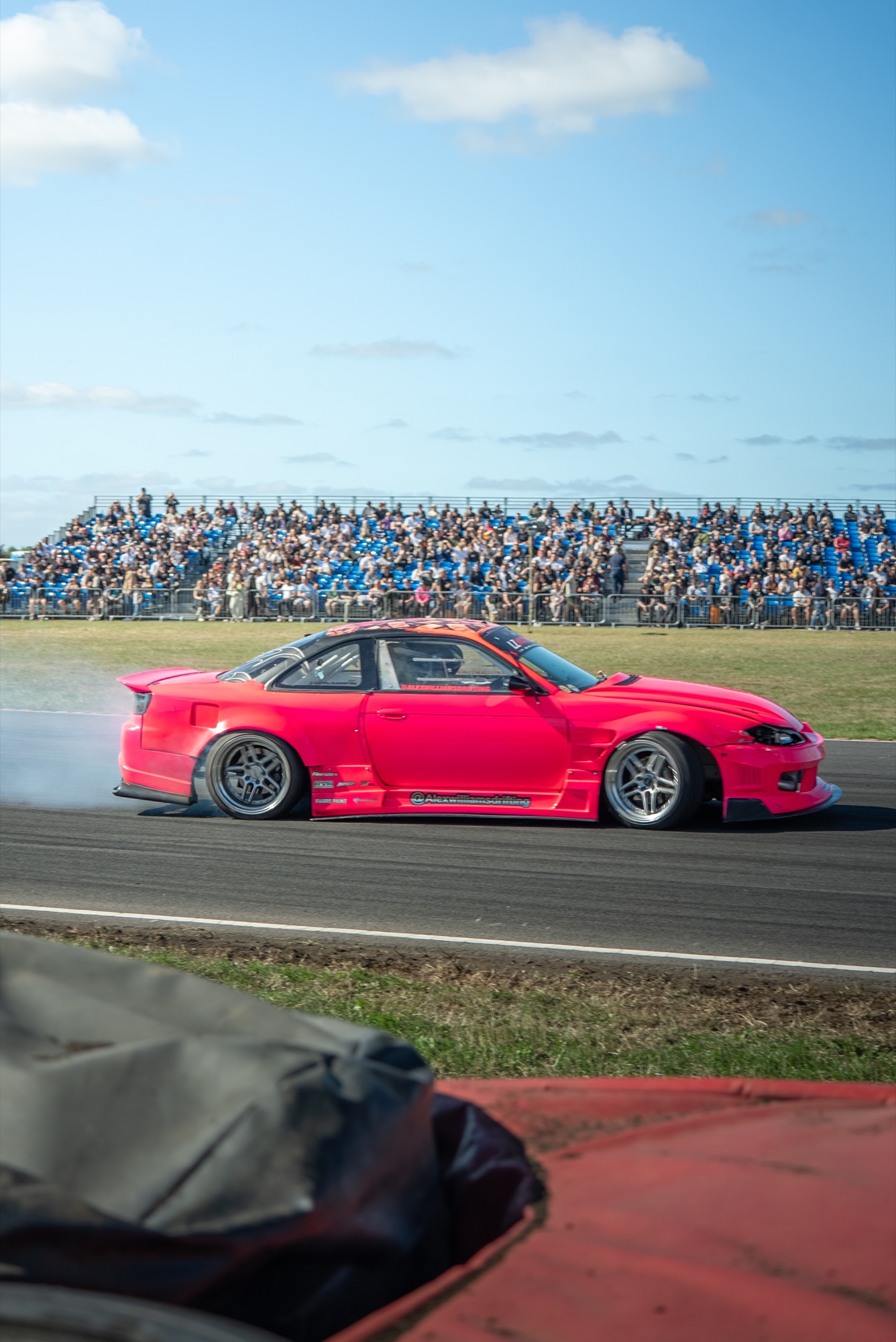 Hot pink Nissan Silvia S15 drifting past a packed grandstand at LZ World Tour