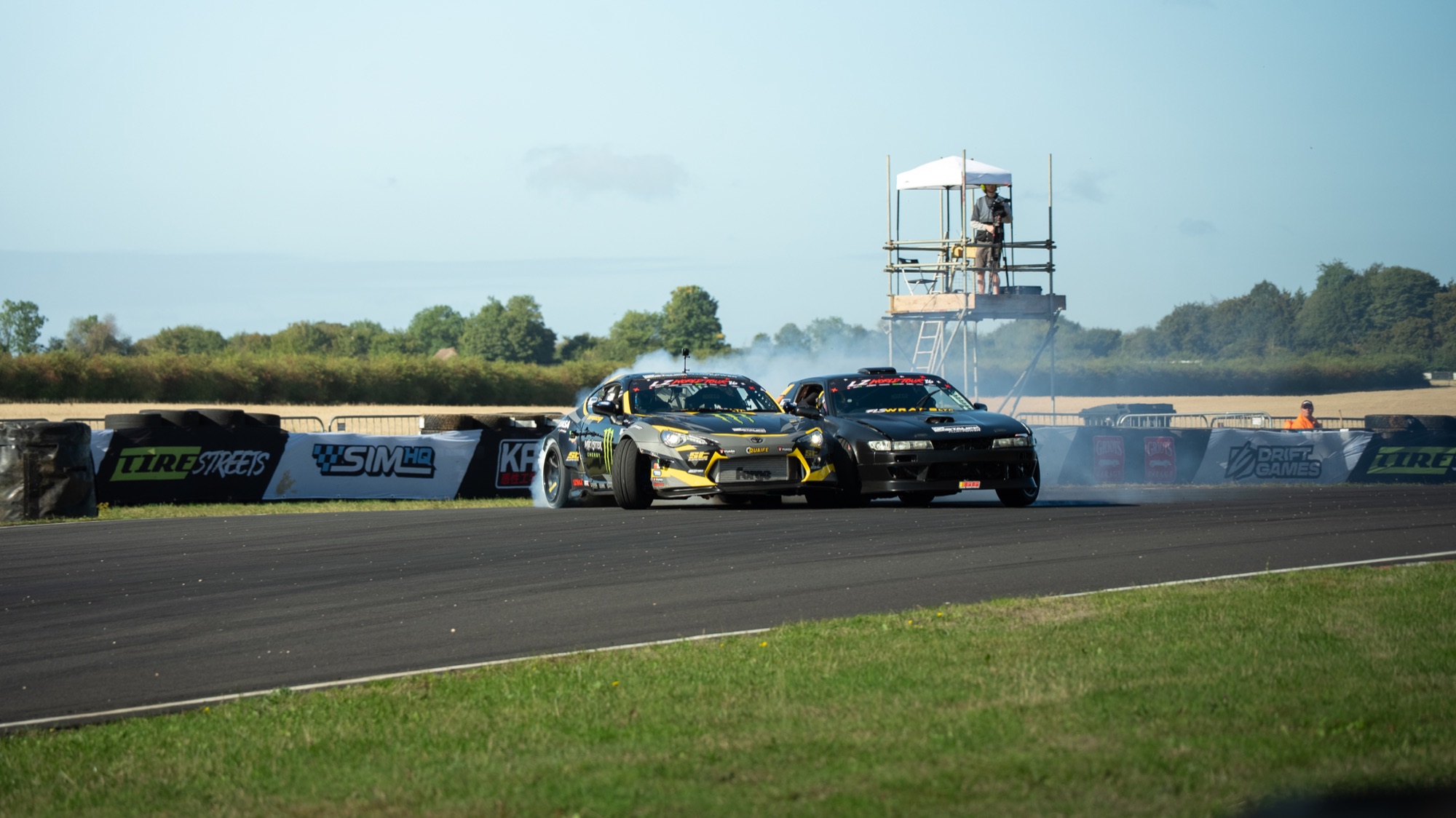 Two drift cars in tandem at LZ World Tour, smoke and a packed infield